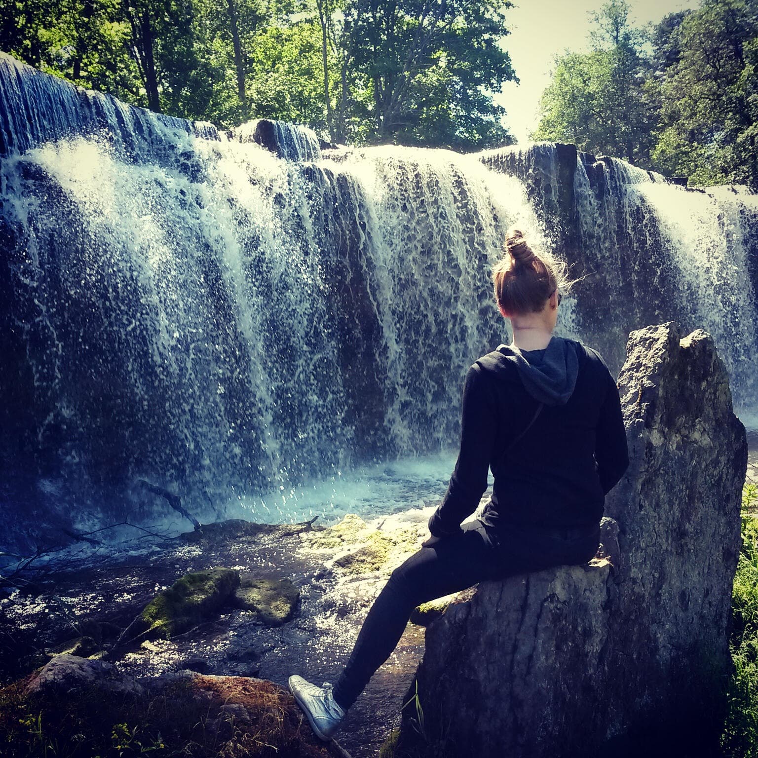 Maria sitting by a waterfall in nature